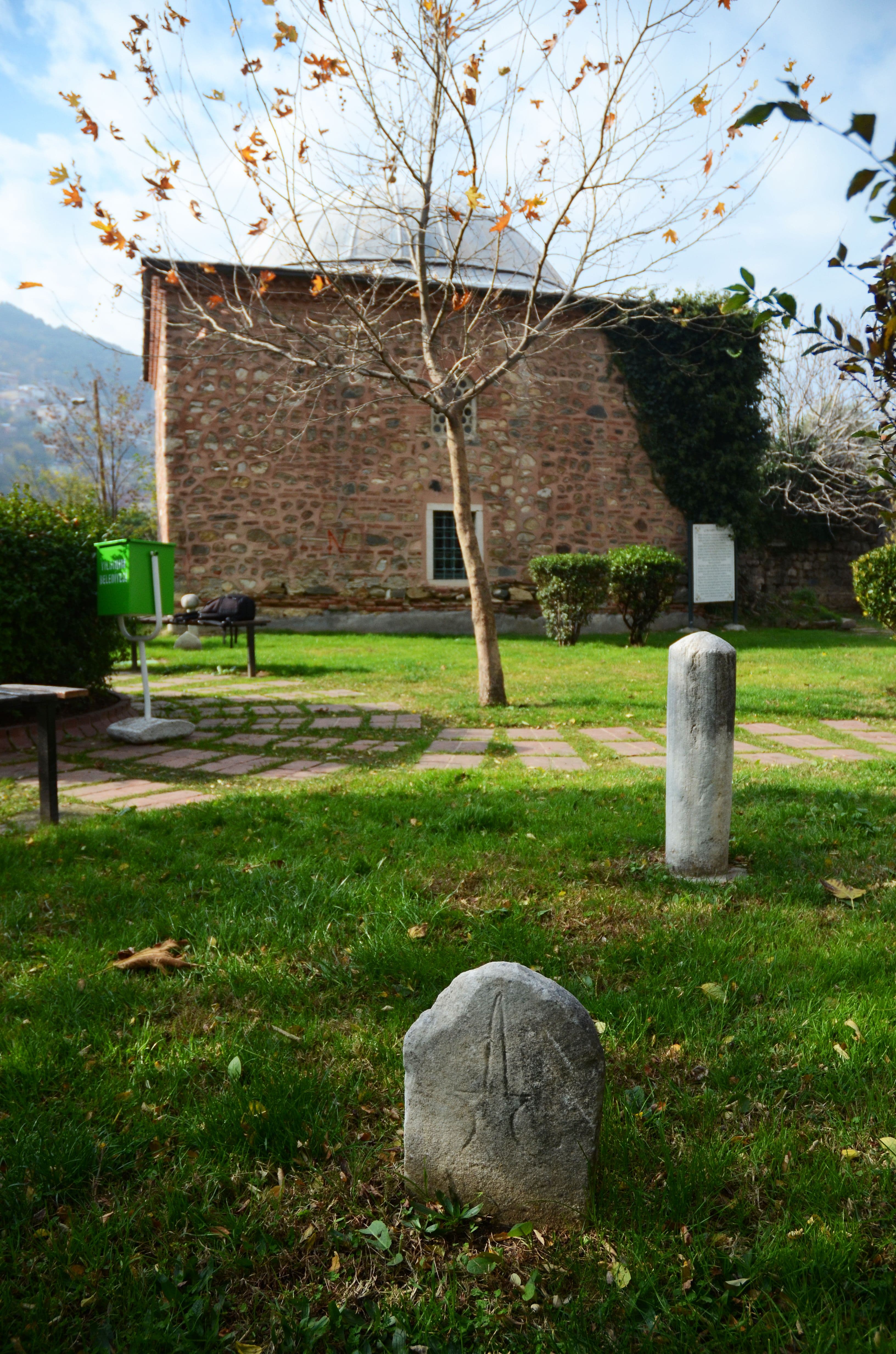 Bursa'daki Çobanbey Türbesi'nin bahçesinde yer alan tarihi mezar taşları ve arka planda görünen türbe binası.