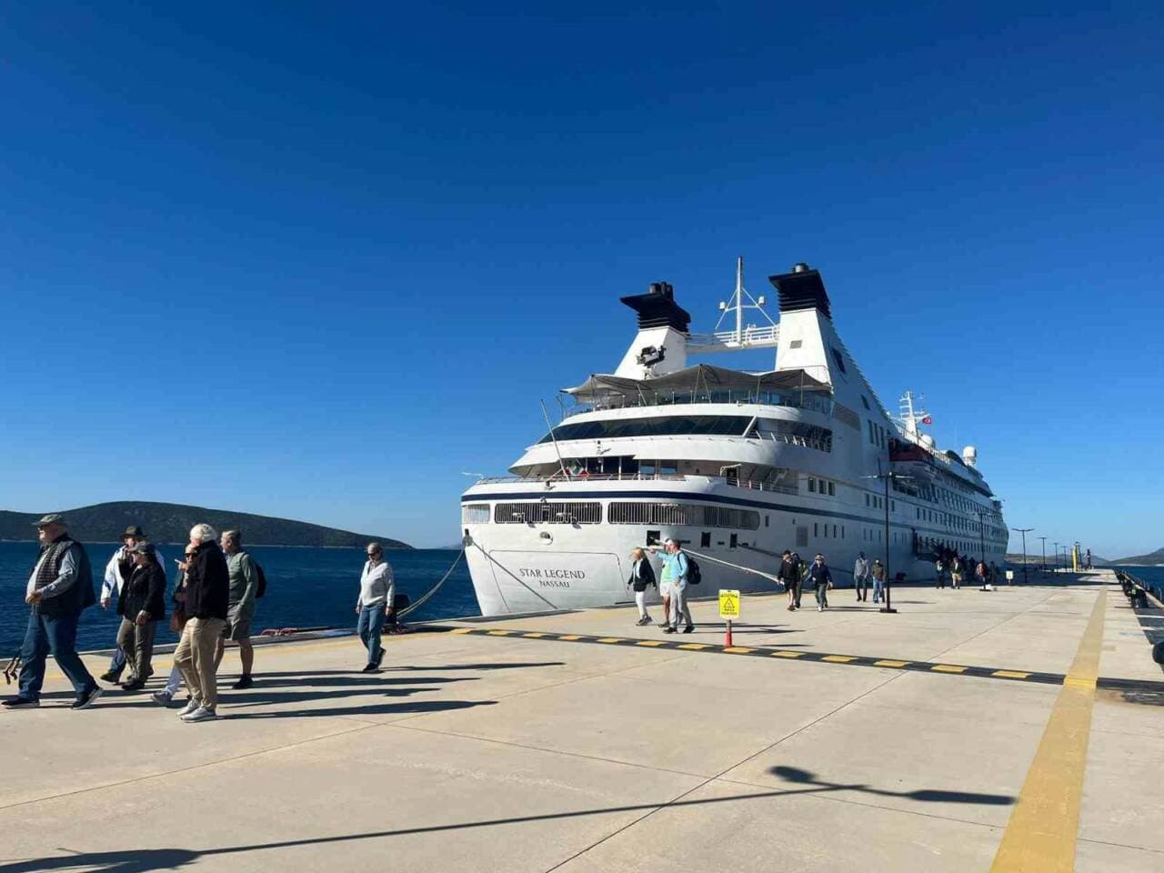 Bodrum Limanı'na yanaşmış Malta bayraklı Star Legend kruvaziyer gemisi ve iskelede yürüyen turistler.