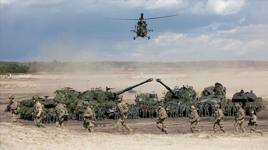 Askeri tatbikat yapan askerler, tanklar ve bir helikopter.