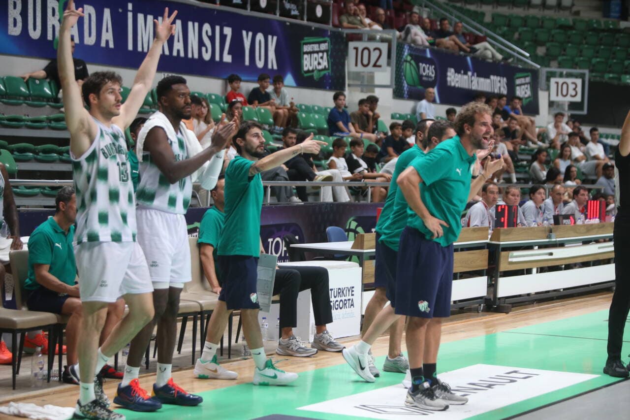 Bursaspor basketbol takımı oyuncuları ve antrenörleri maç sırasında kenar çizgide.