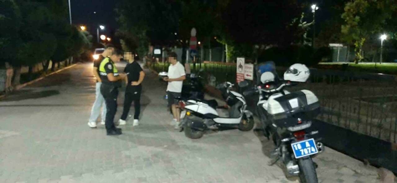 Karacabey'de motosiklet denetimi yapan polis memurları ve denetlenen motosiklet sürücüleri.