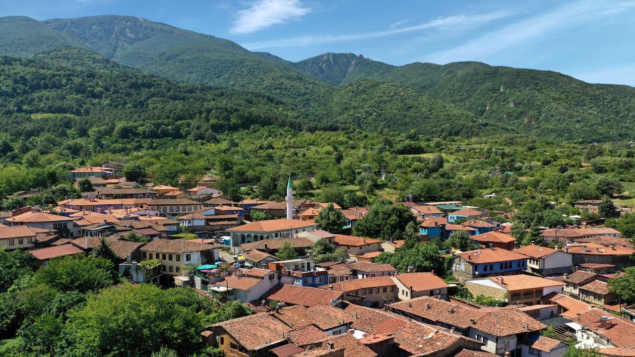 UNESCO Dünya Mirası listesindeki tarihi Cumalıkızık köyünün genel görünümü ve yemyeşil dağ manzarası.