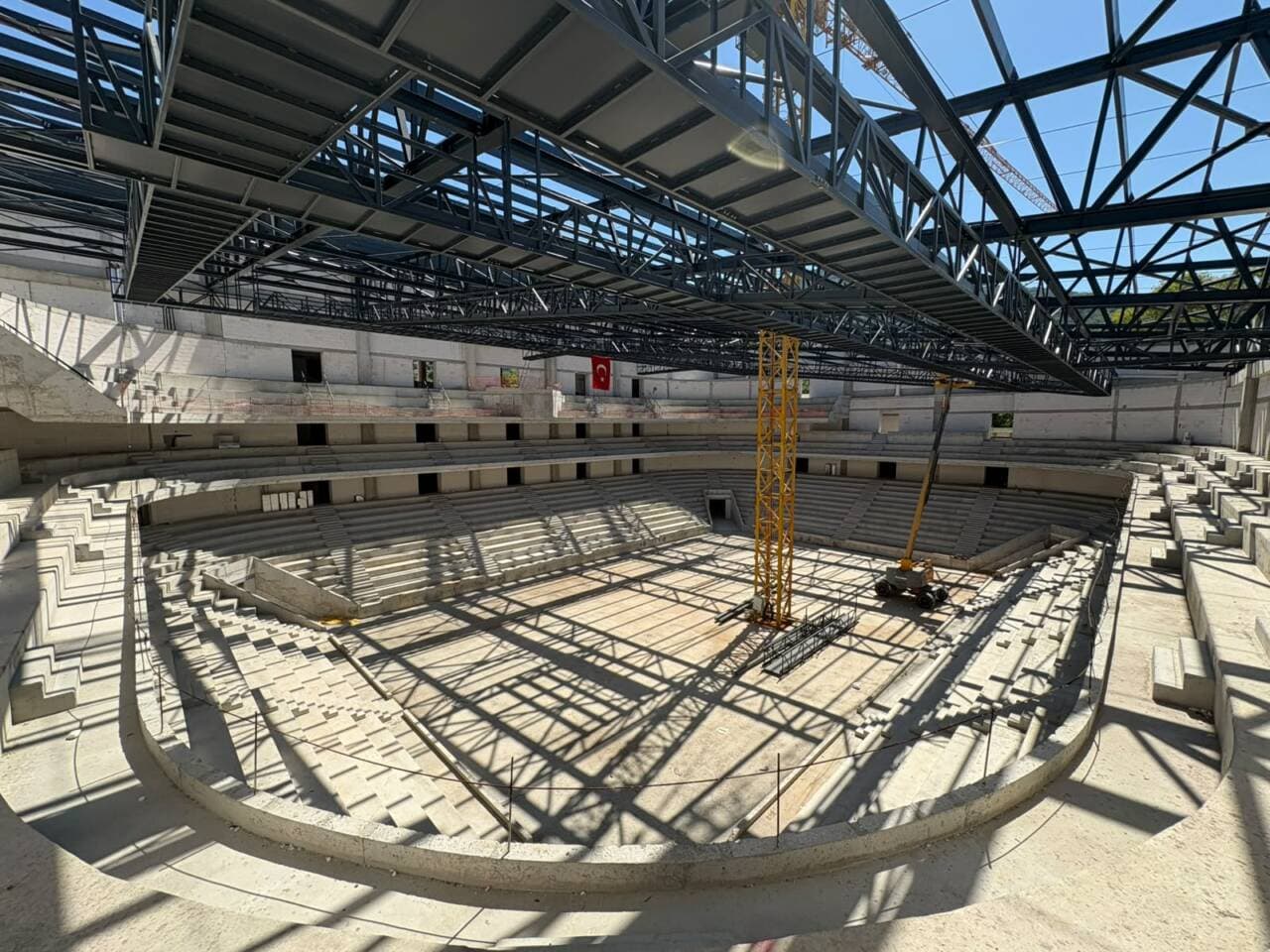 Bursa Atatürk Spor Salonu'nun inşaat halindeki iç görünümü, tribünler ve çelik çatı konstrüksiyonu.