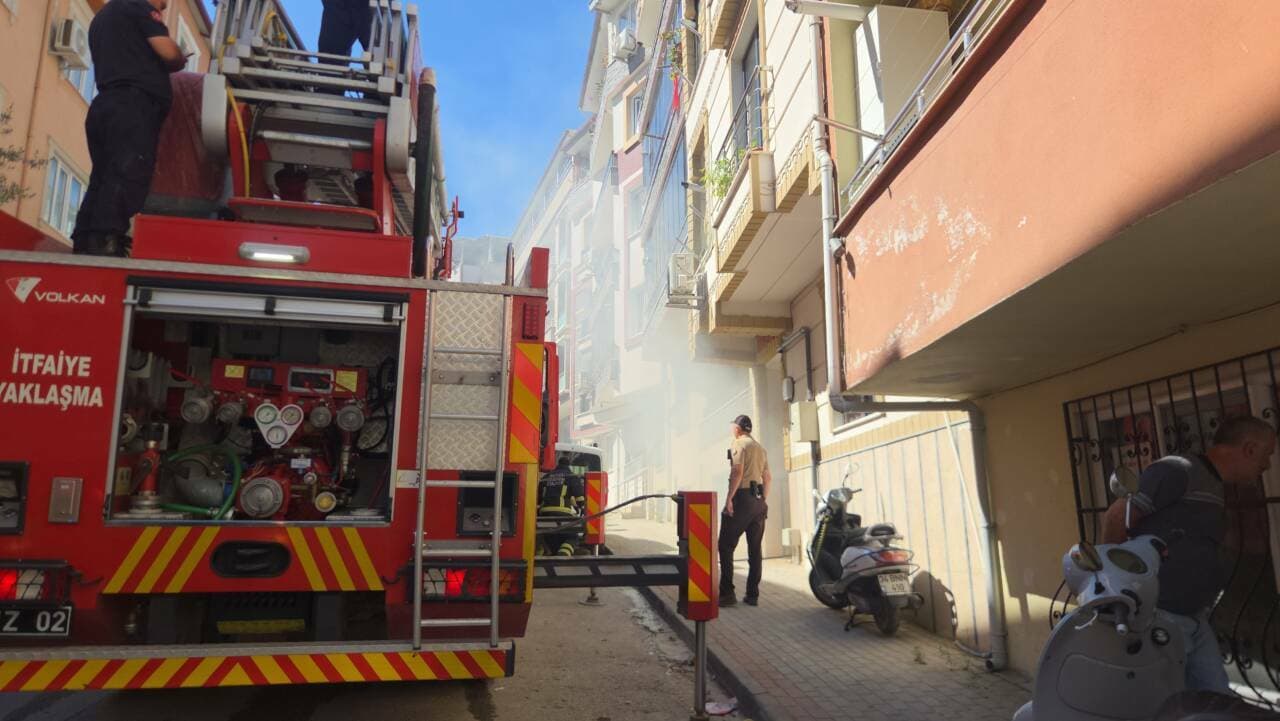 Bursa Orhangazi'de yangın çıkan binanın önünde itfaiye aracı ve dumanlar