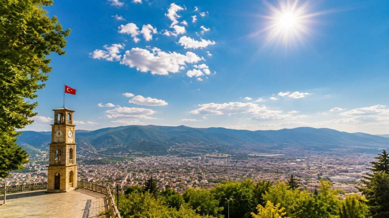 Bursa'nın tarihi saat kulesi ve şehir manzarası, güneşli ve parçalı bulutlu bir havada.