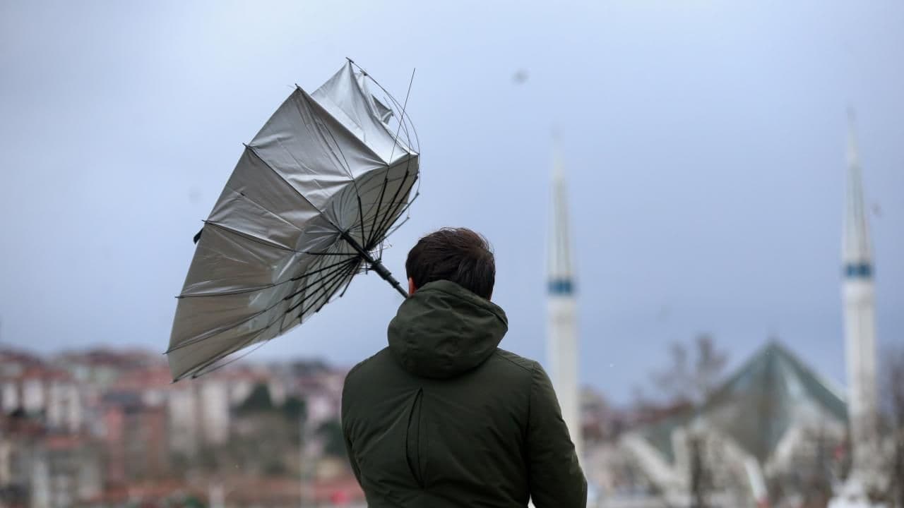Kuvvetli rüzgarda ters dönmüş şemsiye tutan bir kişi.