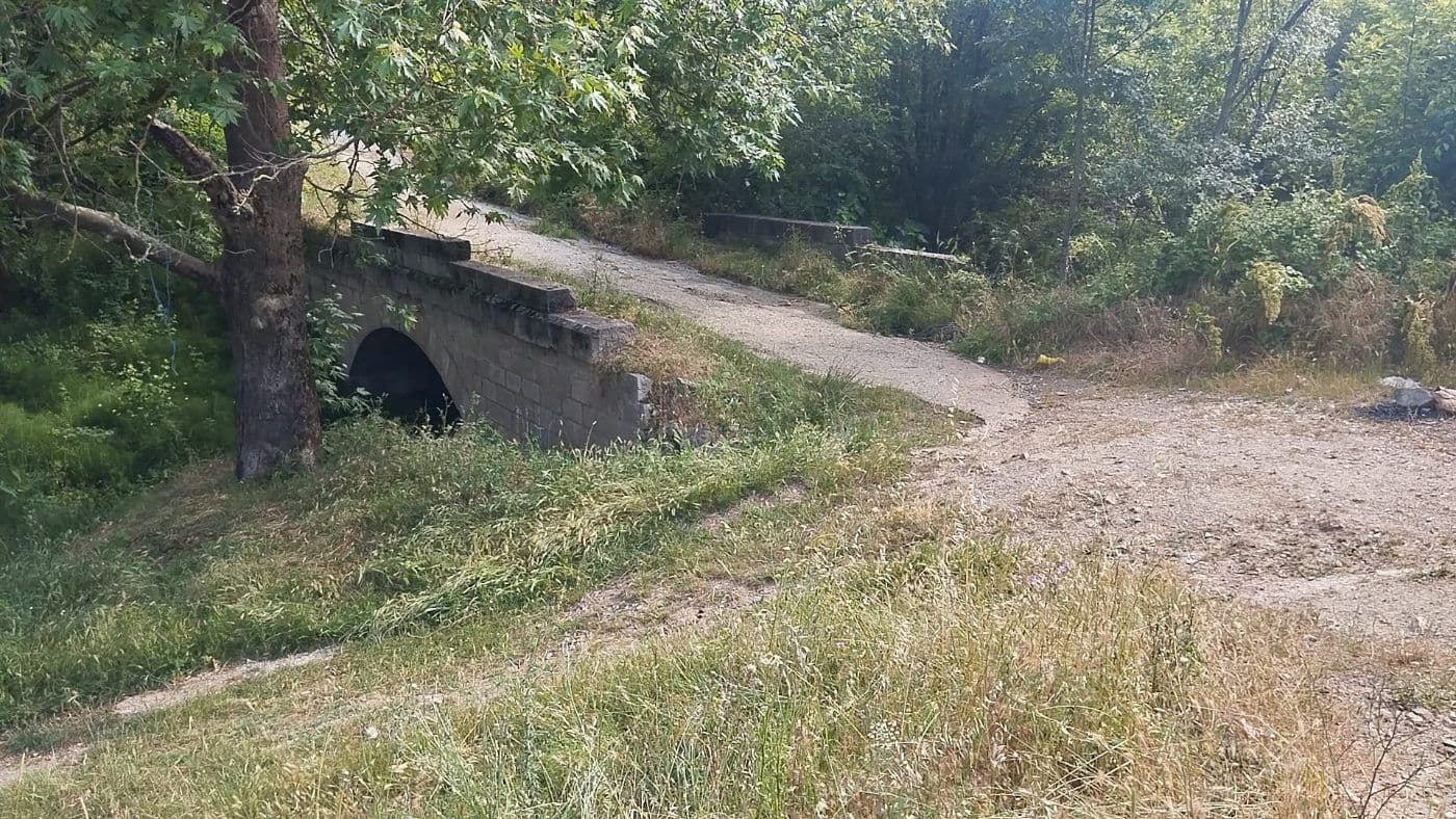 İznik yolu üzerinde, yeşillikler arasında, asfaltın altında kalmış tek kemerli tarihi taş köprü.