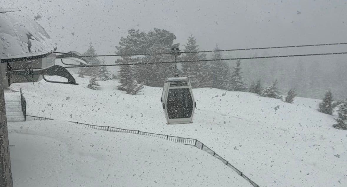 Nisan ayında kar yağan Uludağ'da teleferik ve karla kaplı ağaçlar.