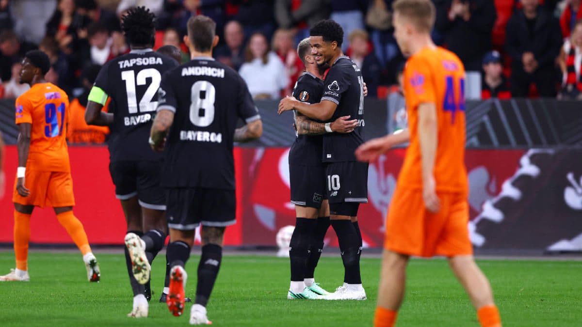 UEFA Avrupa Ligi maçında Bayer Leverkusen forması giyen futbolcular sahada, iki oyuncu gol sevincini paylaşıyor.