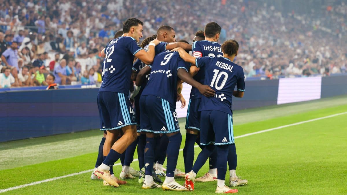 Paris FC futbolcuları maçta gol sevinci yaşıyor, stadyumda seyirciler var.