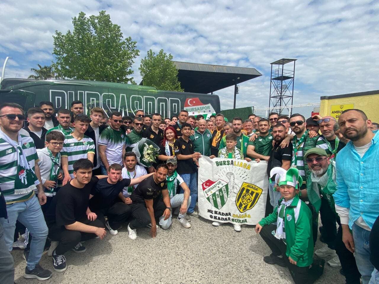 Aliağa ve Bursaspor taraftarları, maç öncesi dostluk pankartı ve çiçeklerle birlikte poz veriyor.