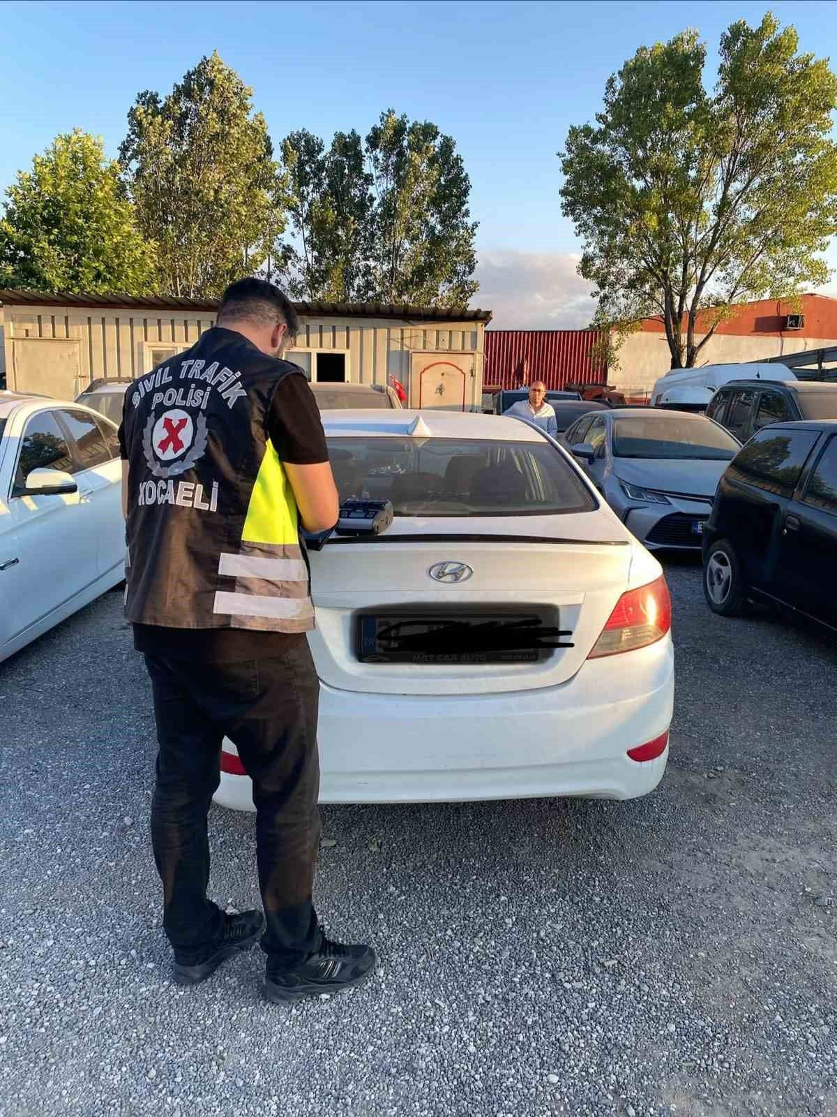 Kocaeli'de korsan taksiye ceza kesen sivil trafik polisi ve beyaz otomobil.