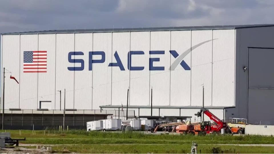 Üzerinde büyük harflerle SpaceX yazan ve yanında Amerikan bayrağı bulunan bir bina.